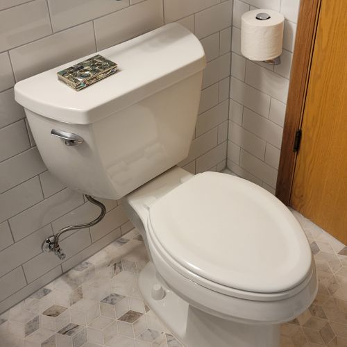 White toilet with subway tile wall and paterned floor tile